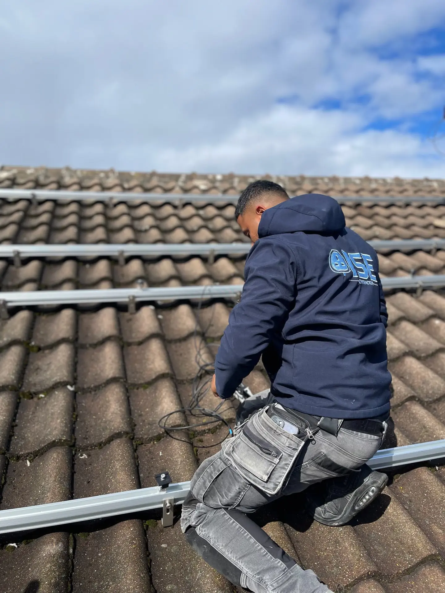 Engineer connecting solar panel cabling on a pitched roof